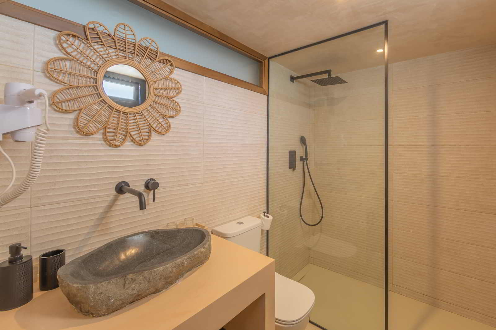 Baño moderno en La Villa del Hotel Punta Sur con lavabo de piedra y ducha con grifería negra.