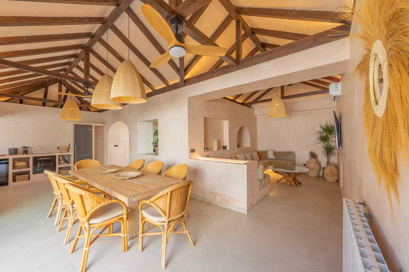 Comedor y salón integrados en La Villa del Hotel Punta Sur con techos altos, mobiliario de fibras naturales y decoración mediterránea.
