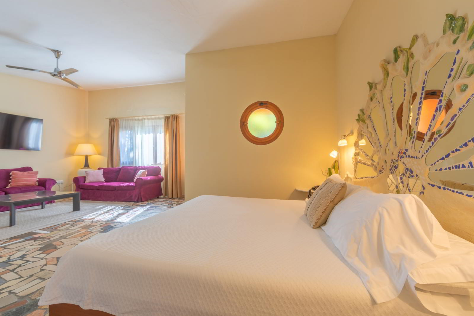Dormitorio de la Habitación Junior Suite con cama doble, cabecero artesanal, iluminación cálida y acceso directo al baño integrado.