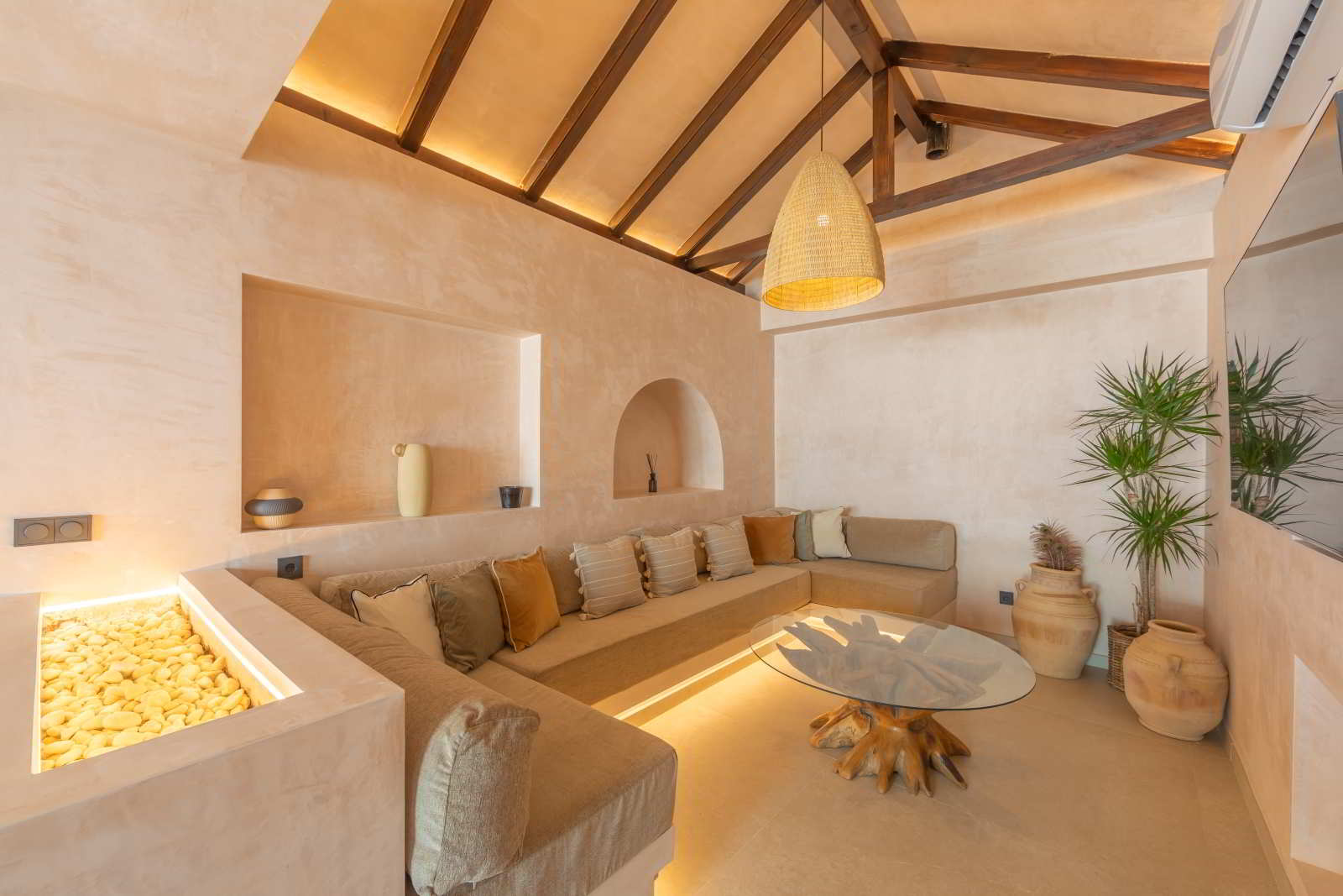 Salón de La Villa del Hotel Punta Sur con sofá esquinero, techo de vigas y decoración natural.