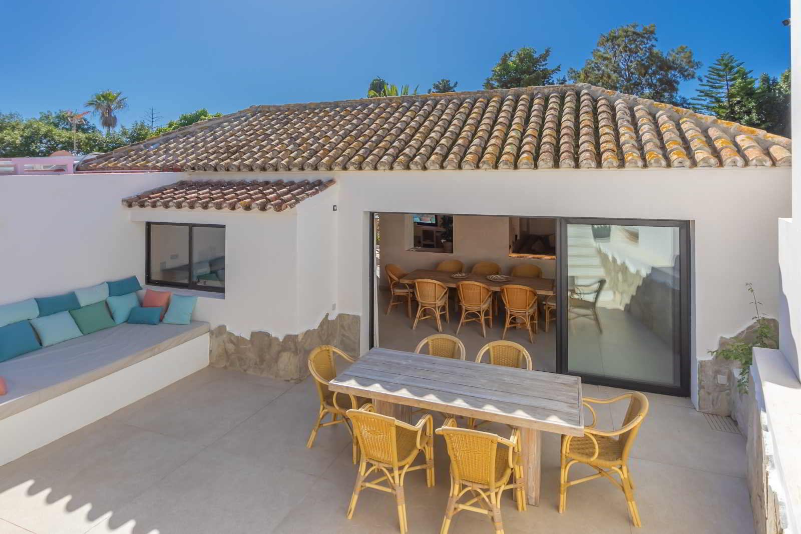 Terraza de La Villa del Hotel Punta Sur con sofá integrado, mesa de comedor y acceso al salón.