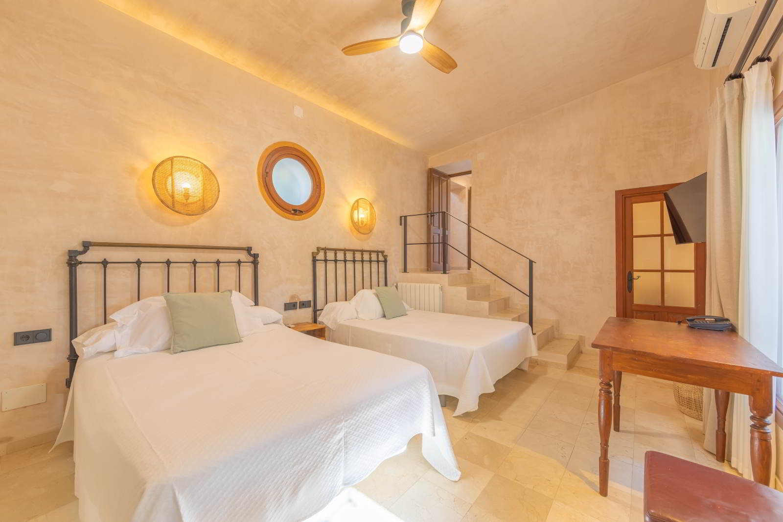 Dormitorio doble con camas de forja y decoración mediterránea en La Villa del Hotel Punta Sur.